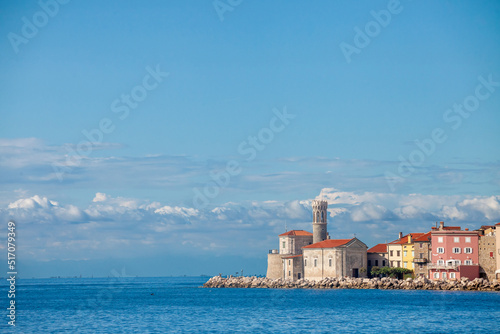 Panorama of  Piran, Slovenia, with Adriatic sea in front, with blue water and sky, on a wharf quay, during a sunny summer afternoon. Piran, or Pirano, is a slovenian city on the adriatic sea in istria