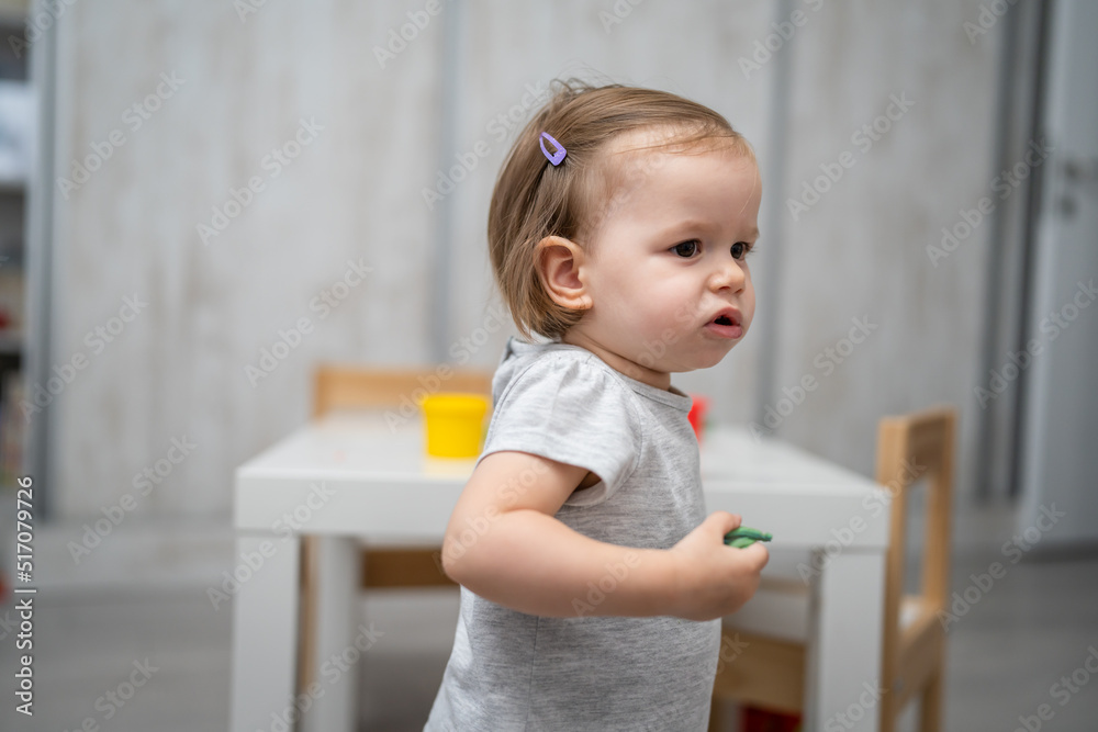 One small caucasian girl little female toddler playing at home in room alone looking to the side copy space growing up and childhood concept copy space domestic life One small caucasian girl little female toddler playing at home in room alone looking to the side copy space growing up and childhood concept copy space domestic life