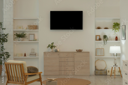 Stylish TV set mounted on wall in room