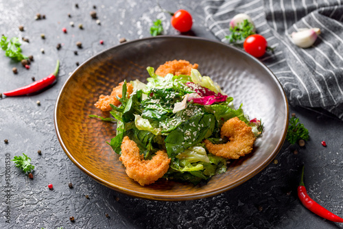 Salad with deep-fried shrimps and mix salad on grey table