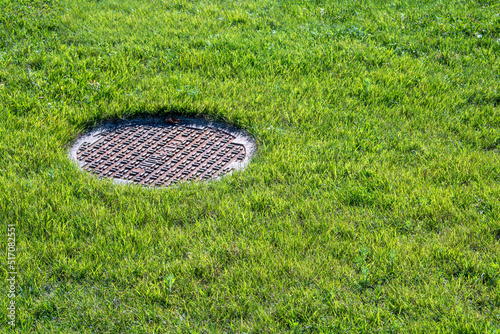 manhole cover on green grass lawn sunny day