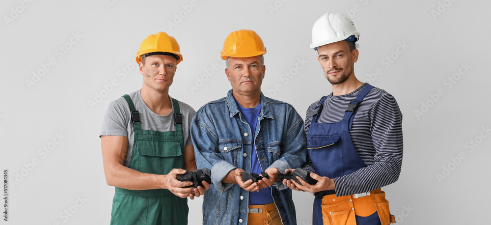Miner men with coal on grey background