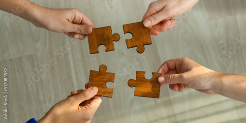People assembling wooden puzzle, top view