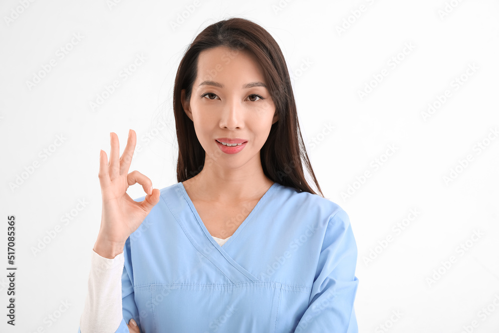 Female Asian nurse showing OK on white background Female Asian nurse showing OK on white background