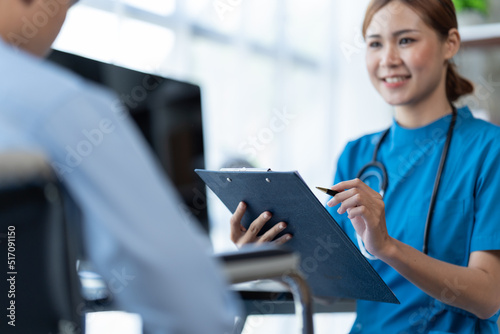 Doctor and patient sitting and talking at medical examination at hospital office, close-up. Therapist filling up medication history records. Medicine and healthcare concept.