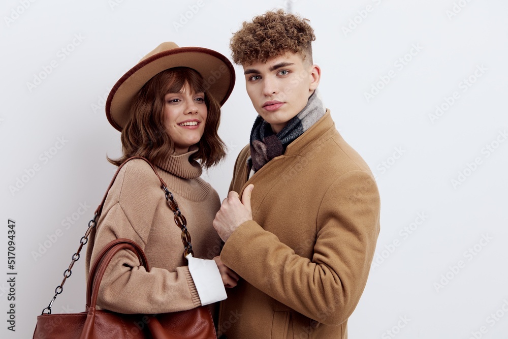 a close horizontal photo of a beautiful, stylish couple in autumn clothes. A woman stands in a hat and holds a bag on her shoulder, snuggling up to a man with a joyful smile on her face a close horizontal photo of a beautiful, stylish couple in autumn clothes. A woman stands in a hat and holds a bag on her shoulder, snuggling up to a man with a joyful smile on her face