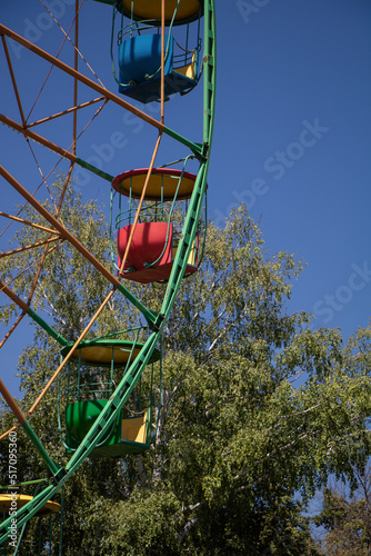 City amusement park. Ferris wheel with colored cabins.