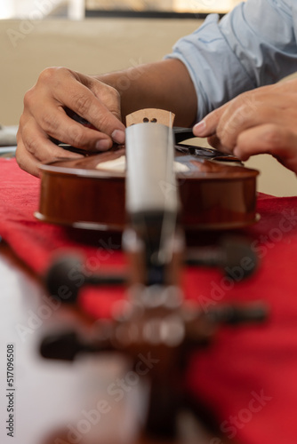 Vertical photo of the hands of an artisan repairing a violin © Guillermo Spelucin