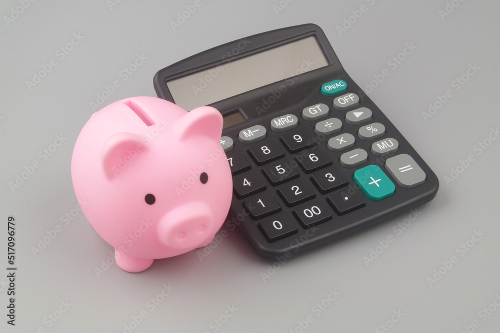 Pink piggy bank with calculator on grey background. Saving money concept. Pink piggy bank with calculator on grey background. Saving money concept.