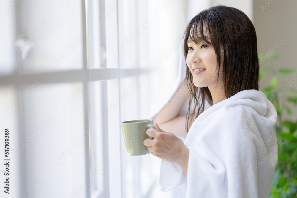窓際で髪の毛を拭く女性 窓際で髪の毛を拭く女性