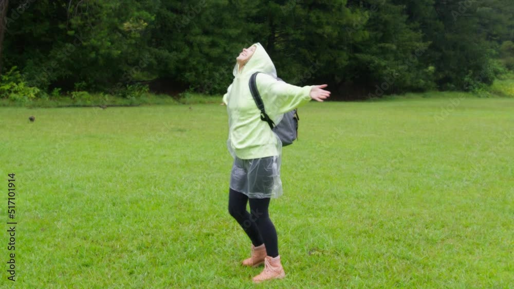 Slow motion around carefree young woman feeling free and smiling while refreshing under rain on background of green trees. Concept of life, freedom, nature, adventure, purity, water, tropical, exotic Slow motion around carefree young woman feeling free and smiling while refreshing under rain on background of green trees. Concept of life, freedom, nature, adventure, purity, water, tropical, exotic