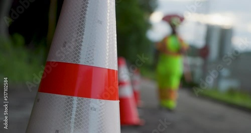 Road Construction Flagger Walking with Stop / Slow Sign Past Traffic Cones