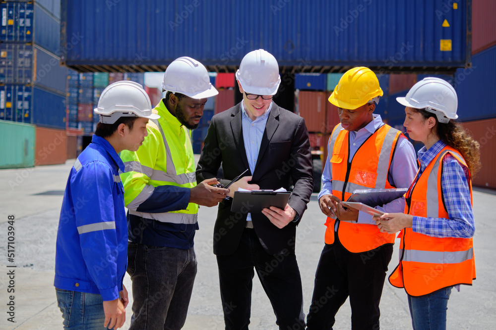 Group of multiracial workers in safety uniforms and hardhats work at logistics terminal dock with stacks of containers, loading control, and management shipping goods, cargo transportation industry. Group of multiracial workers in safety uniforms and hardhats work at logistics terminal dock with stacks of containers, loading control, and management shipping goods, cargo transportation industry.