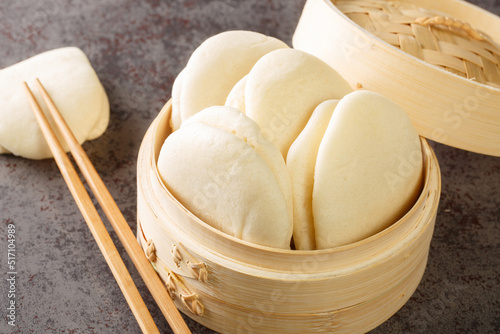 Chinese steamed buns Gua bao in a bamboo steamer close-up on the table. horizontal photo