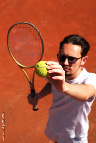 male tennis player playing on the court holding the ball to serve © Irina