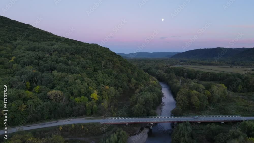 View from above. Picturesque road bridge across the river against the backdrop of a bright sunset. View from above. Picturesque road bridge across the river against the backdrop of a bright sunset.