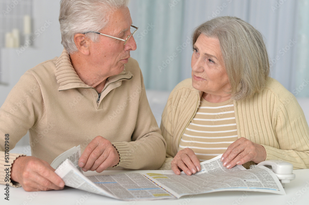 Senior couple portrait with newspaper at home