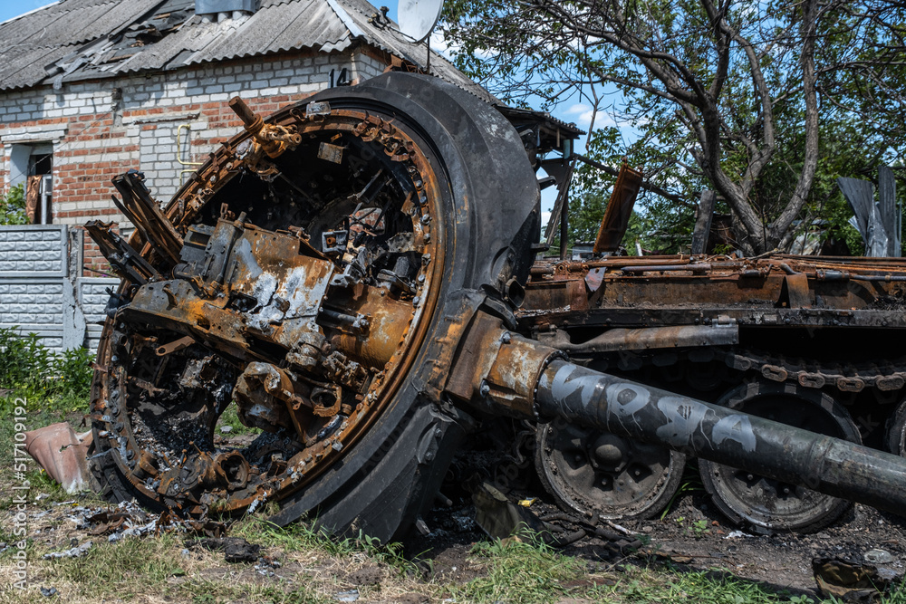Fototapeta premium A burnt Russian tank near a residential building. War in Ukraine 2022. Russian missiles in Kharkiv countryside Ukraine. Russian aggression. Russian attack on Ukraine.