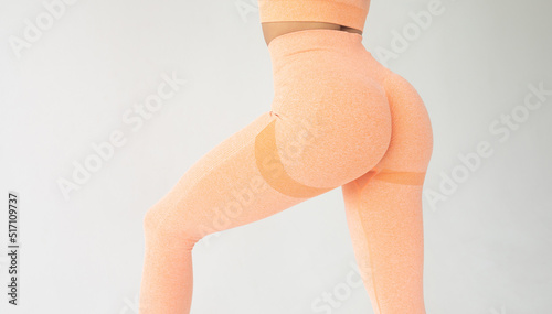 Fitness model in leggings with beautiful buttocks. Sporty trained woman booty on grey background. photo