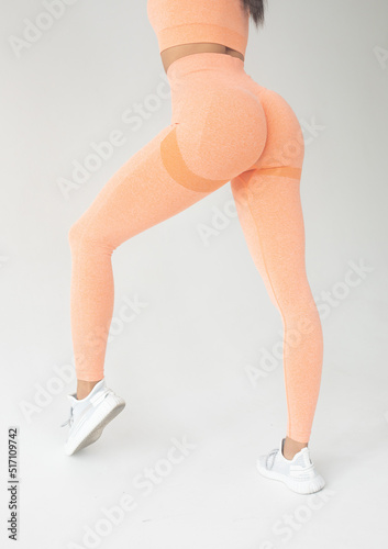 Fitness model in leggings with beautiful buttocks. Sporty trained woman booty on grey background.