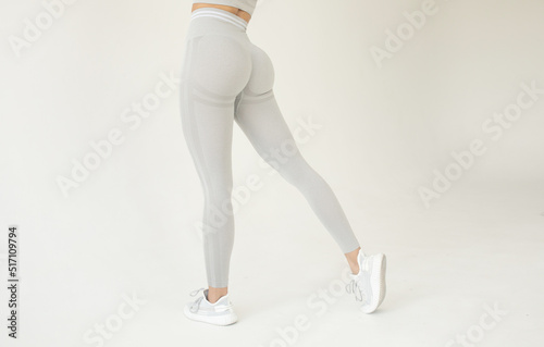 A big woman booty in leggings on grey background.