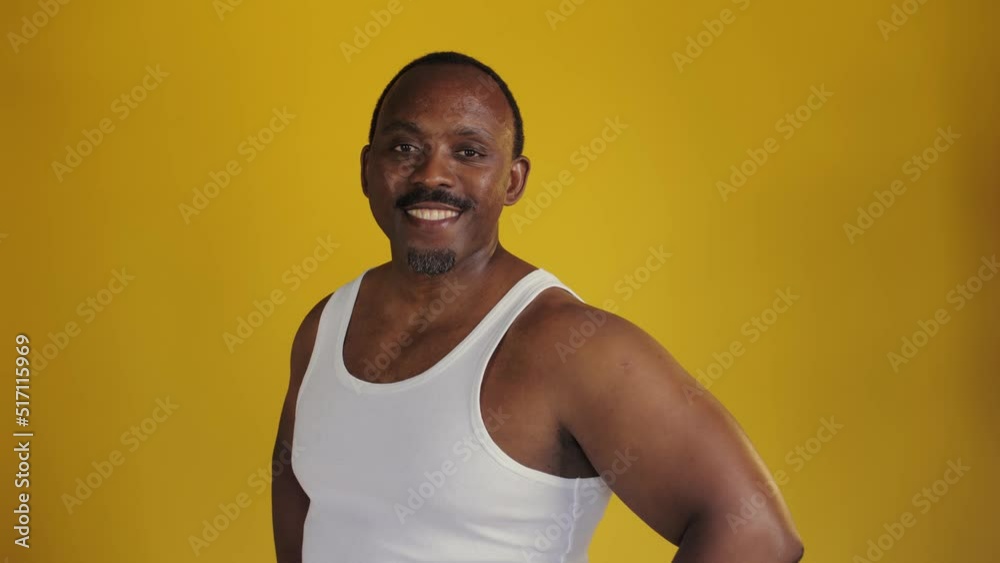 Portrait of an African man on a yellow background. Man smiling for the camera. Hands at his waist and smiling for the camera Portrait of an African man on a yellow background. Man smiling for the camera. Hands at his waist and smiling for the camera