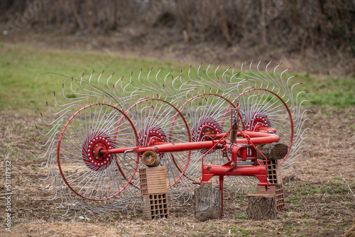 Old rusty vintage Rotary Hay Collector on a green grass on farmland, Freshly painted in red. Agricultural machinery that connects to a tractor. photo