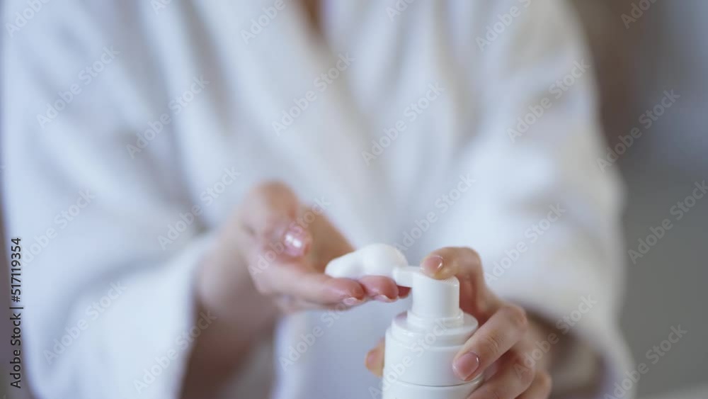 Beautiful young woman applying cleansing foam onto face in bathroom Beautiful young woman applying cleansing foam onto face in bathroom