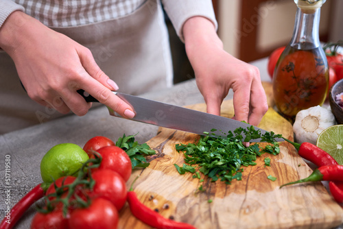 making salsa dip sauce - woman cutting and chopping cilantro or parsley on wooden cutting board