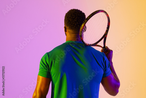 Image of back view of african american male tennis player in violet and yellow neon lighting © vectorfusionart