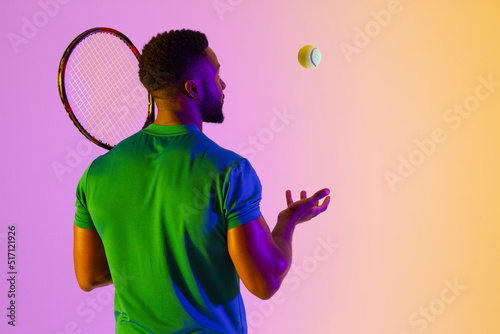 Image of back view of african american male tennis player in violet and yellow neon lighting © vectorfusionart