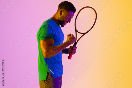 Image of successful african american male tennis player in violet and yellow lighting © vectorfusionart