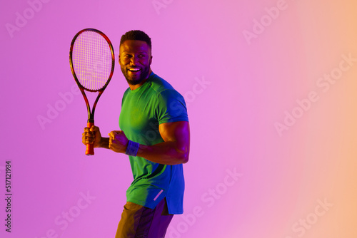 Image of happy african american male tennis player in violet and yellow lighting © vectorfusionart