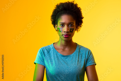 Image of african american female soccer fan with flag of portugal in yellow lighting © vectorfusionart