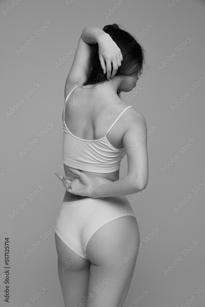 Portrait of young beautiful girl with dark hair posing in white underwear. Black and white photography aesthetics Portrait of young beautiful girl with dark hair posing in white underwear. Black and white photography aesthetics