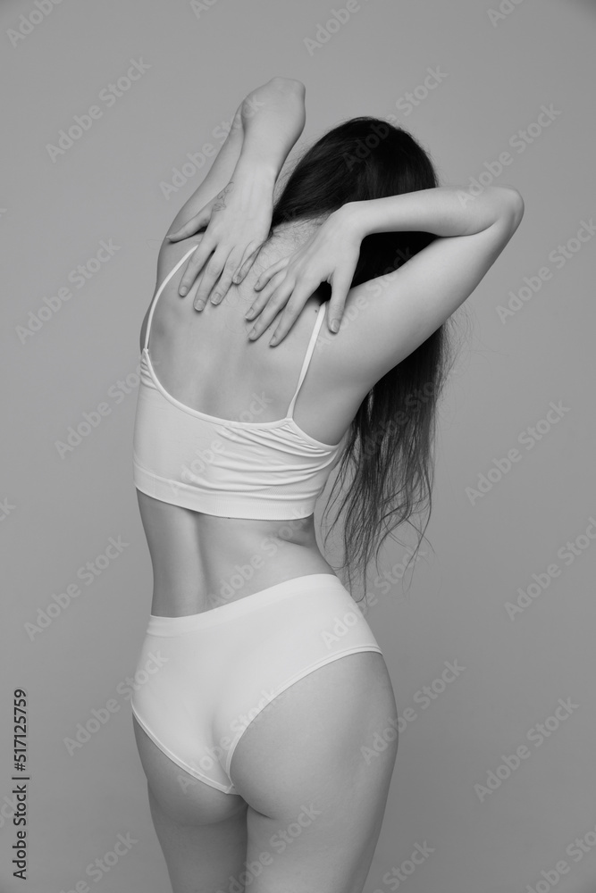 Obraz premium Portrait of young girl with slim tender figure posing in white underwear. Black and white photography aesthetics