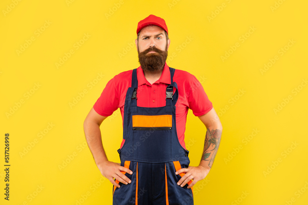 serious bearded man repairer in work clothes on yellow background serious bearded man repairer in work clothes on yellow background