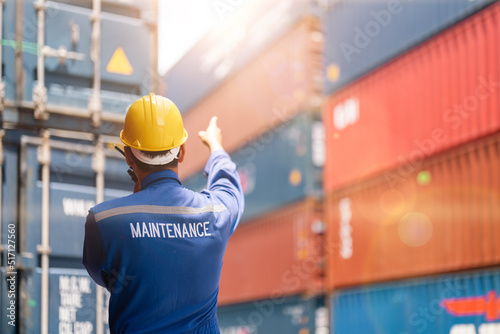 Maintenance engineer using walkie talkie to communication with colleague at container yard.