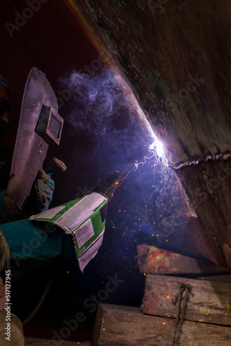 Working person welding a metal with a welding machine. 