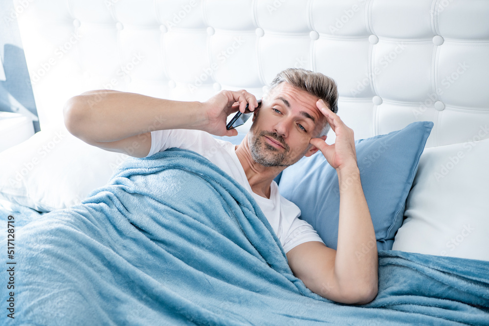 Obraz premium awaken mature man in bed speaking on phone