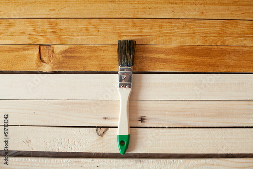 brush on wooden slats. Half of the them is covered and the other is not. wood treatment from fungus and dampness with wood stain