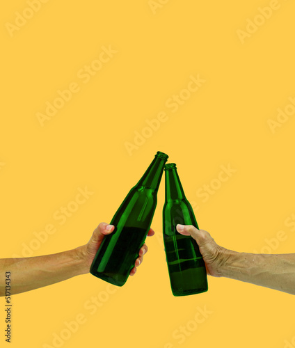 Couple hands holding beer bottles and clanging on yellow bacground . Party, Holiday, Summer, Friendship Concept. Cheers in pub..
