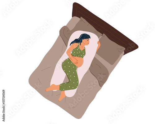 
Top view of a young pregnant woman in pajamas sleeping on a maternity pillow on the bed. Healthy night sleep. Comfortable position for sleeping, Preparing for childbirth. Health and pregnancy care. 