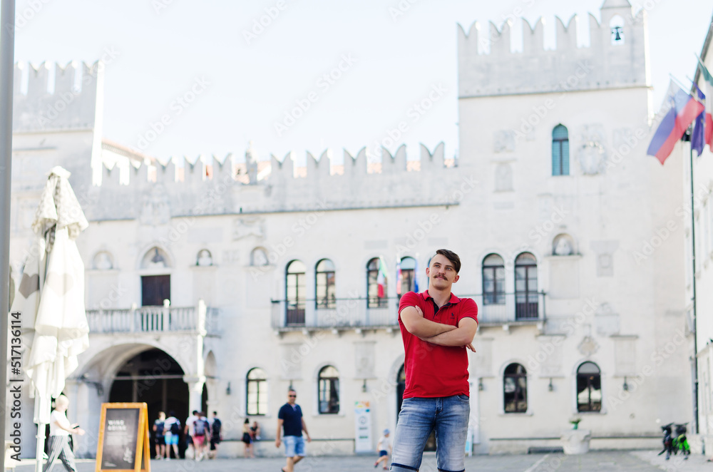 Young happy handsome bearded man, tourist walking in old city of Koper. Summer vacation. Sunglasses. Lifestyle portrait