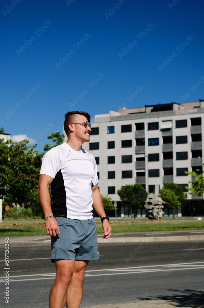 Young happy handsome bearded man, tourist relaxing in city park of Koper. Smiling. Summer vacation. Sunglasses.