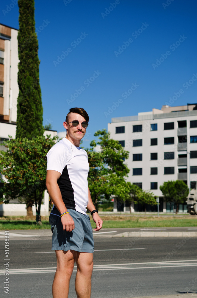 Young happy handsome bearded man, tourist relaxing in city park of Koper. Smiling. Summer vacation. Sunglasses.