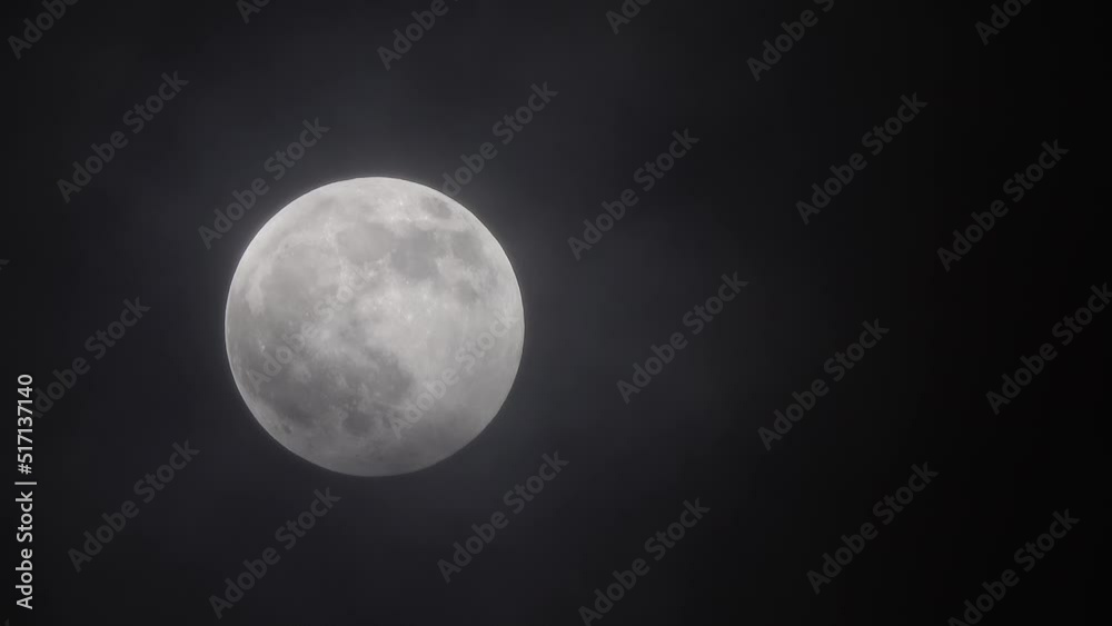 full moon moving between clouds