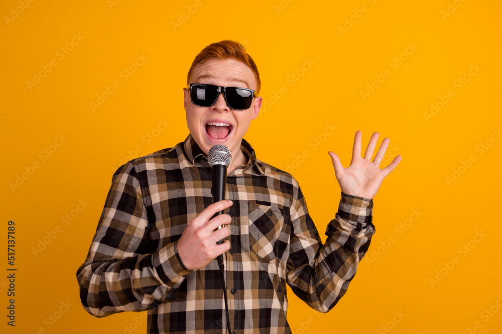 Photo of young excited guy sing song karaoke microphone mic star isolated over yellow color background Photo of young excited guy sing song karaoke microphone mic star isolated over yellow color background