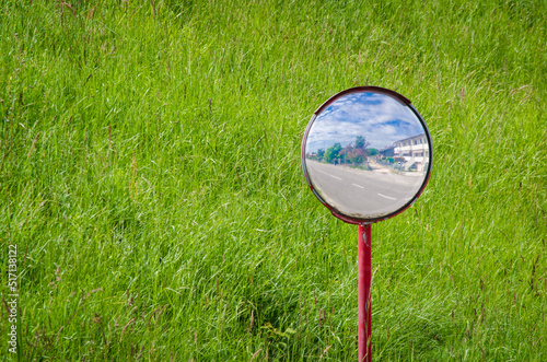 Uno specchio stradale con dietro l'argine verde di un fiume riflette un incrocio photo