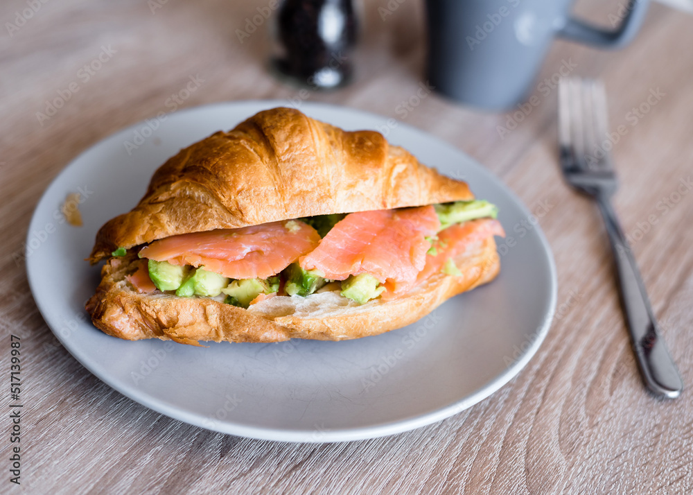 Fresh croissant with salmon and avocado. Healthy and tasty breakfast. Healthy diet. Close-up. Fresh croissant with salmon and avocado. Healthy and tasty breakfast. Healthy diet. Close-up.